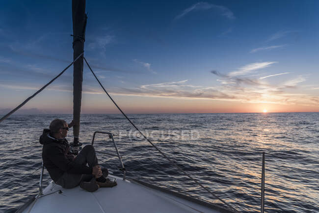 Senior man sitting aboard yacht watching sunset, Porquerolles, Provence-Alpes-Cote d'Azur — Stock Photo