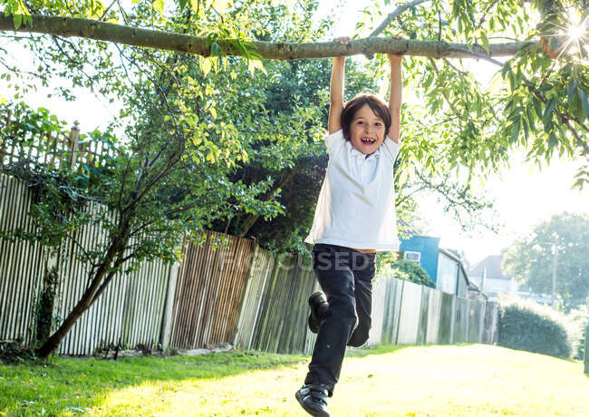 Garçon avoir amusant balançant sur arbre branche — Photo de stock
