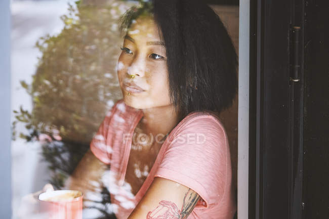 Woman gazing in cafe window seat, Shanghai French Concession, Shanghai, China — Stock Photo