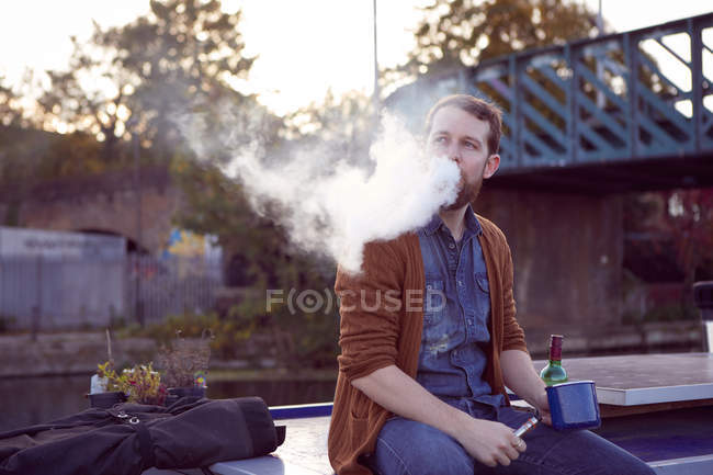 Mann raucht elektronische Zigarette auf Kanalboot — Stockfoto