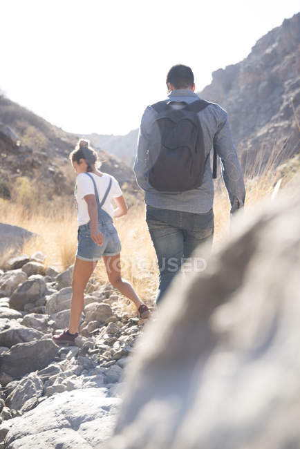 Blick von hinten auf junges Wanderpaar, das über Felsen im Tal, Las Palmas, Kanarische Inseln, Spanien wandert — Stockfoto
