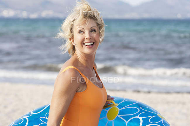 Senior woman carrying inflatable on beach, Palma de Mallorca, Spain — Stock Photo