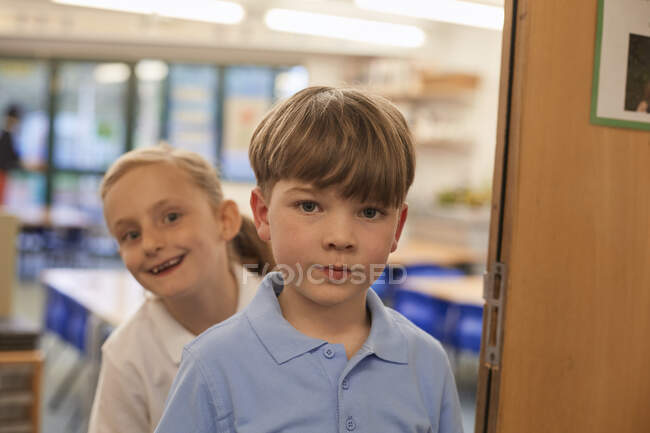 Portrait of schoolboy and girl in classroom at primary school — Stock Photo
