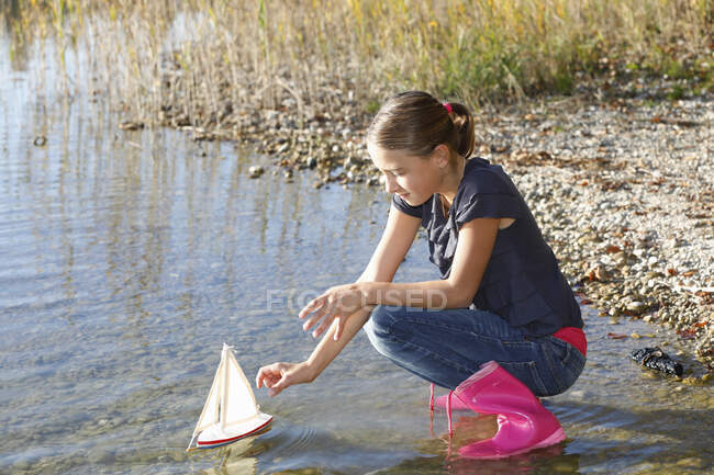 Jovem flutuante barco de brinquedo na água — Fotografia de Stock