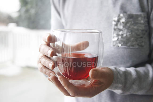 Cropped image of Woman holding glass of red tea at home — Stock Photo