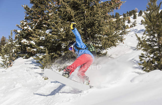 Male snowboarder boarding down on mountain — Stock Photo
