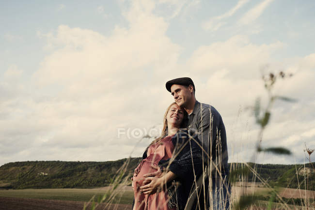 Портрет счастливой беременной пары в поле — стоковое фото
