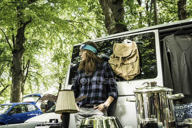 Female leaning against camper van at second hand stall — Stock Photo
