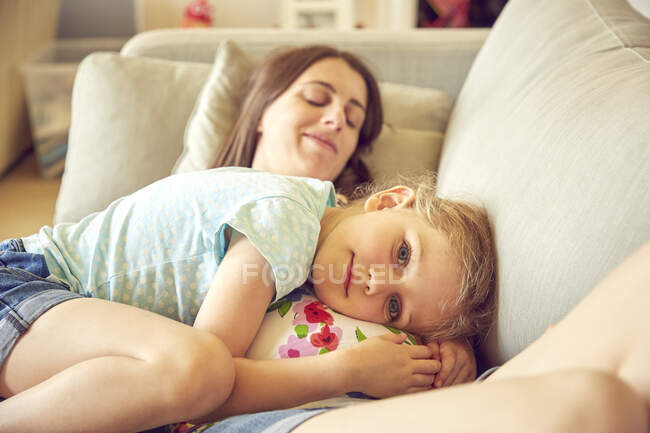 Retrato de niña abrazándose y descansando sobre el estómago de la madre embarazada - foto de stock