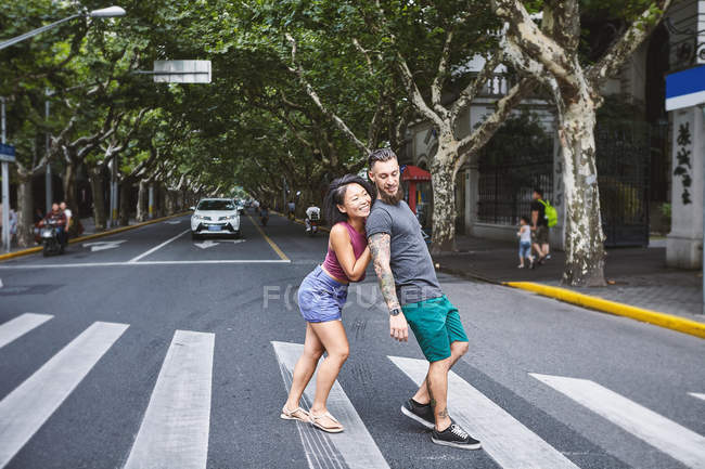 Mulher empurrando namorado na travessia de pedestres, Shanghai French Concession, Shanghai, China — Fotografia de Stock