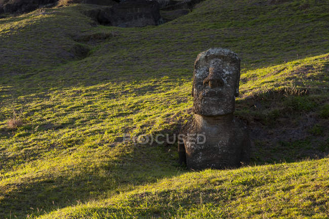 Vista lejana de estatua de piedra en colinas verdes, Isla de Pascua, Chile - foto de stock