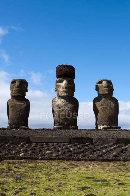 Vista a distanza di statue in pietra sulla collina verde, Isola di Pasqua, Cile — Foto stock