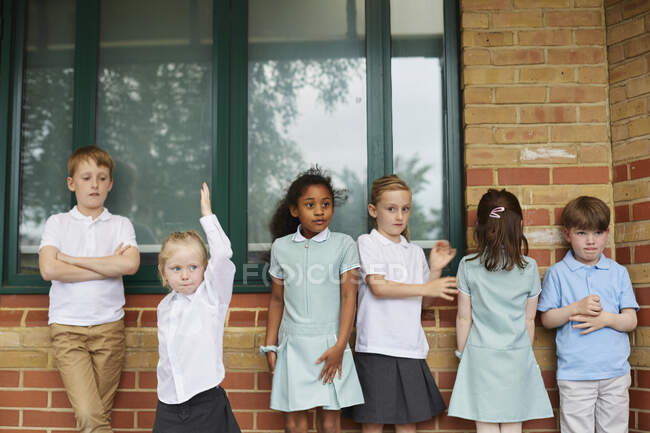 Школьницы и мальчики, стоящие у здания начальной школы — стоковое фото