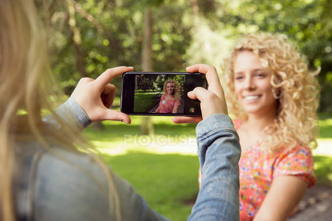 Femme prenant la photo d'un ami en utilisant un smartphone — Photo de stock