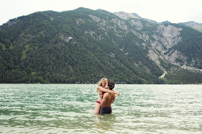 Пара талии глубоко в воде поцелуи, Achensee, Инсбрук, Тироль, Австрия, Европа — стоковое фото