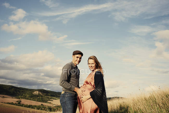 Портрет беременной пары на склоне холма — стоковое фото
