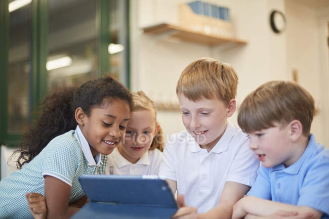 Écoliers et filles regardant tablette numérique en classe à l'école primaire — Photo de stock