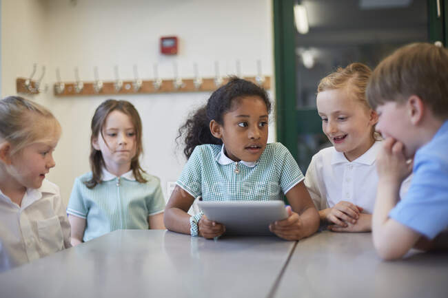 Шкільні дівчата і хлопчик використовують цифрову табличку на уроці в початковій школі. — стокове фото