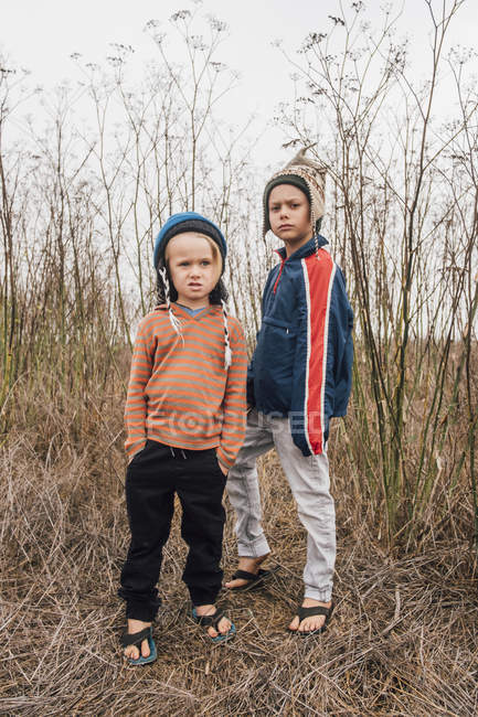 Portrait de deux frères en bonnets tricotés faisant des visages — Photo de stock