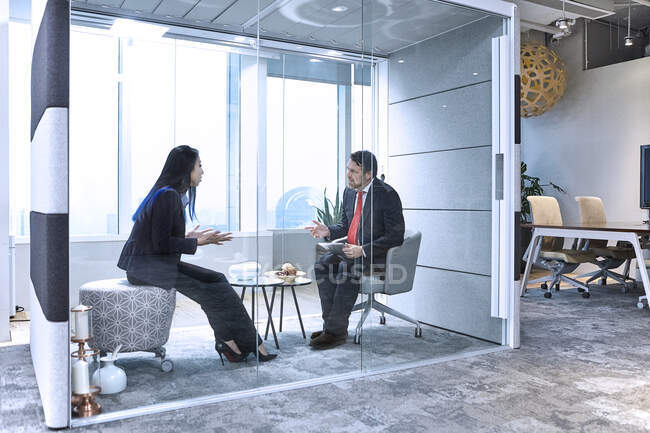 Коллеги встречаются в стеклянной капсуле в офисе — стоковое фото
