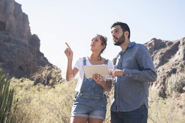 Jovem casal caminhando olhando para cima e apontando do vale, Las Palmas, Ilhas Canárias, Espanha — Fotografia de Stock