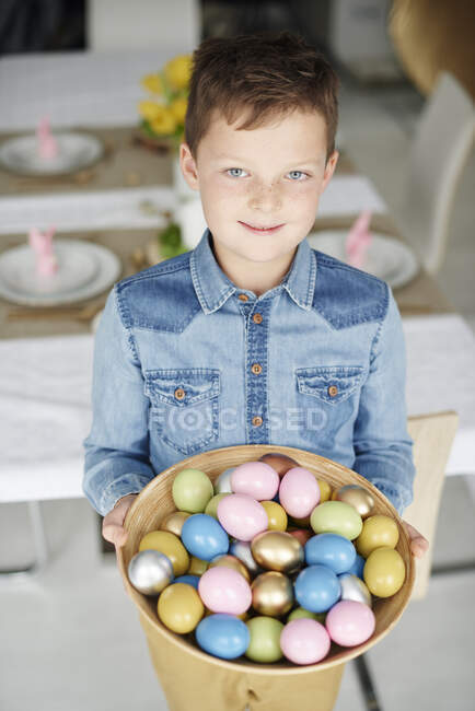 Portrait d'un garçon tenant un bol d'œufs de Pâques colorés — Photo de stock