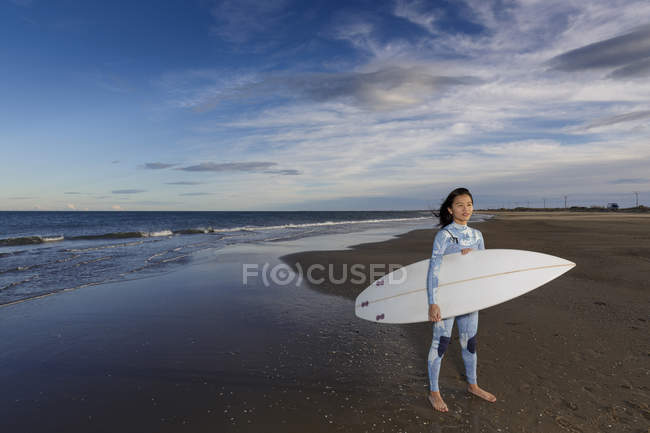 Portrait of young female surfer standing on beach — Stock Photo