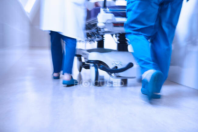 Vista posteriore ritagliata dei medici che spingono la barella nel corridoio — Foto stock