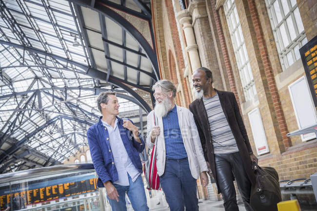 Trois hommes mûrs à la gare, marchant ensemble — Photo de stock