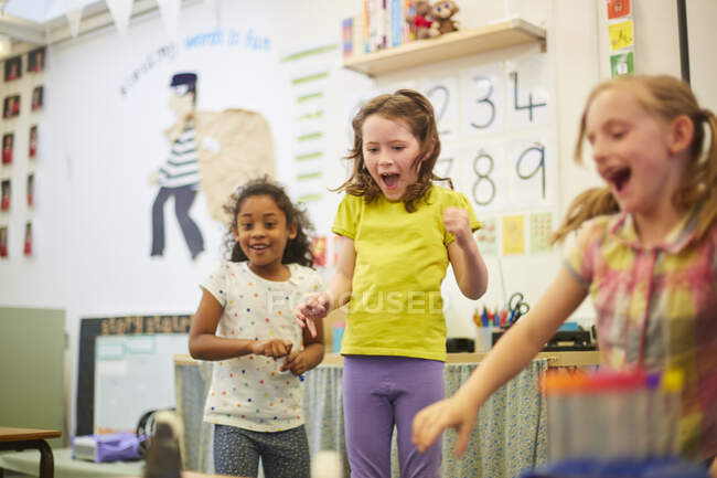 Primary schoolgirls fooling around in classroom — Stock Photo