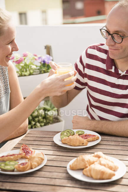 Giovane donna che consegna succo d'arancia colazione al fidanzato al tavolo patio — Foto stock