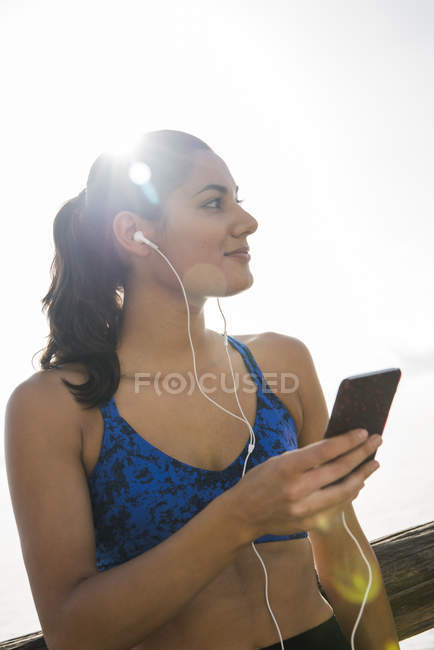 Молодая женщина обучает и слушает музыку смартфона — стоковое фото