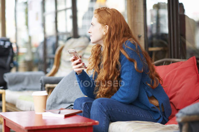 Женщина в кофейне с помощью мобильного телефона — стоковое фото