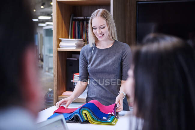 Женщина смотрит на образцы текстиля улыбаясь — стоковое фото