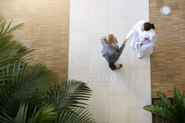 Médica e jovem, apertando as mãos, vista elevada — Fotografia de Stock