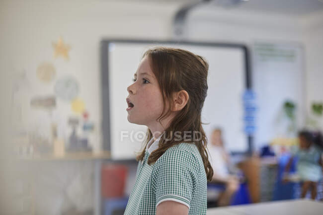 Écolière répondant en classe à l'école primaire — Photo de stock