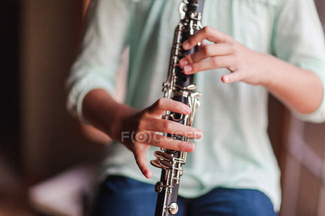 Image recadrée du jeune clarinettiste jouant de la clarinette dans la chambre — Photo de stock