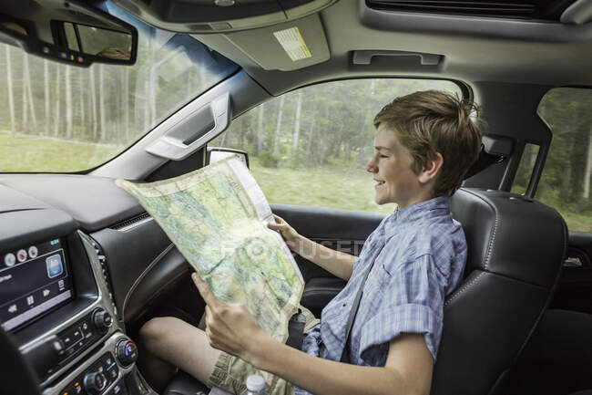 Boy on road trip reading map — Stock Photo
