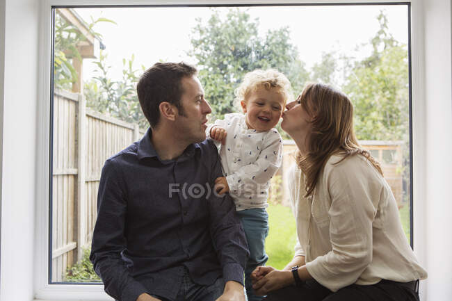Parents and baby boy playing by patio door to garden — Stock Photo