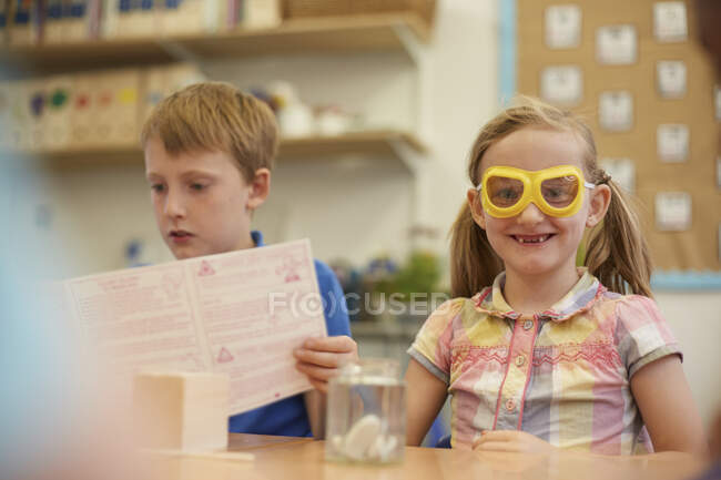 Primary schoolboy and girl doing experiment in classroom — Stock Photo