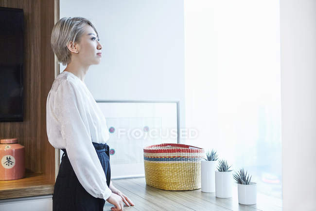 Вид женщины в офисе сбоку, выглядывающей из окна — стоковое фото