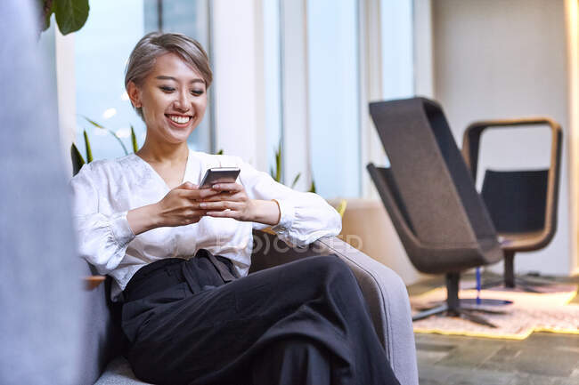 Donna d'affari utilizzando smartphone sorridente — Foto stock