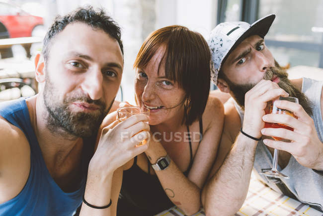 Retrato de tres jóvenes amigos bebiendo cócteles - foto de stock