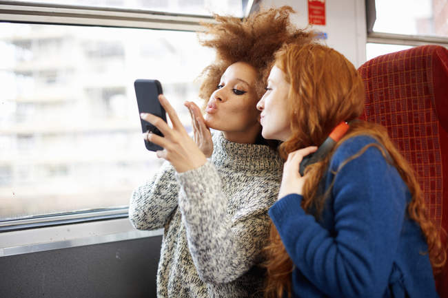 Дві молоді жінки беруть селфі в поїзді — стокове фото