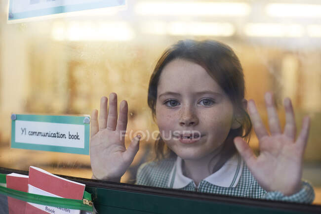 Retrato de estudante com as mãos na janela da sala de aula na escola primária — Fotografia de Stock