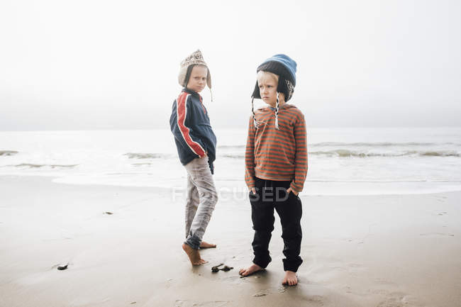 Ritratto di due fratelli in piedi sulla spiaggia — Foto stock