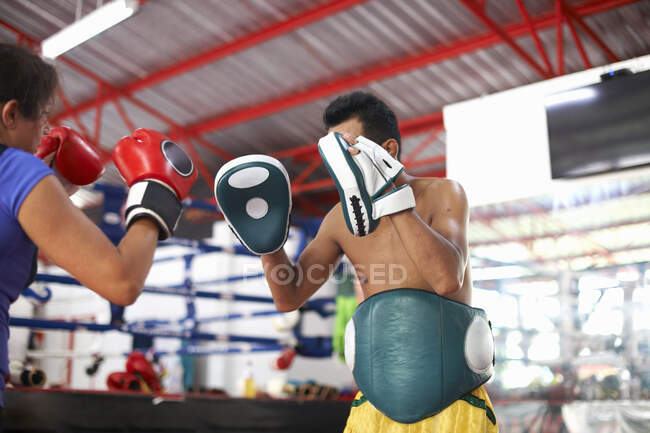 Femme mûre pratiquant la boxe avec entraîneur masculin dans la salle de gym — Photo de stock