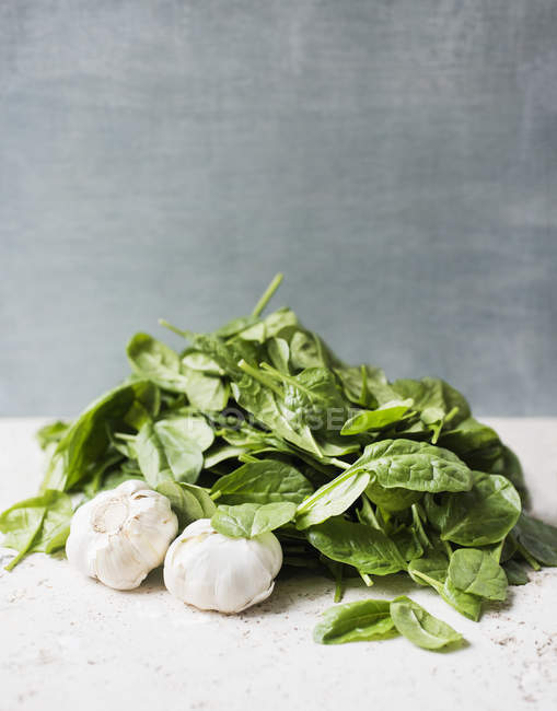 Fresh spinach leaves and garlic on table — Stock Photo