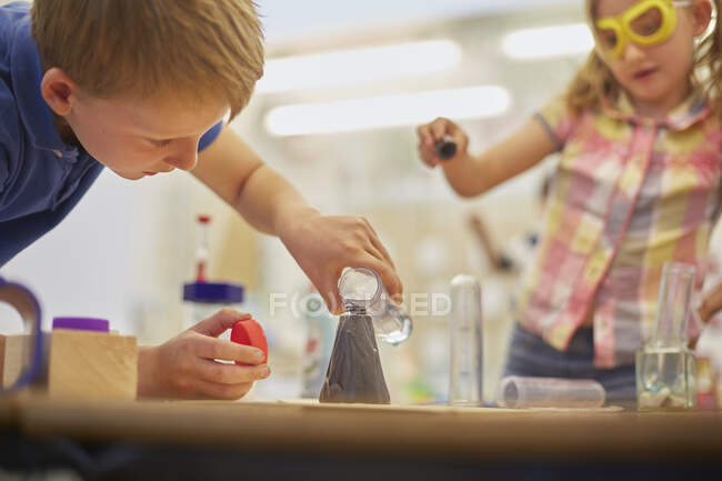Початковий школяр і дівчинка проводять експеримент пробірки в класі — стокове фото