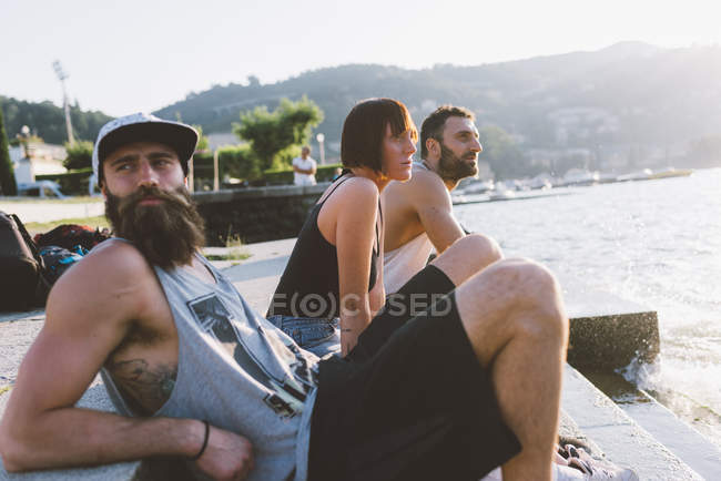 Tres jóvenes amigos mirando el lago Como, Lombardía, Italia - foto de stock